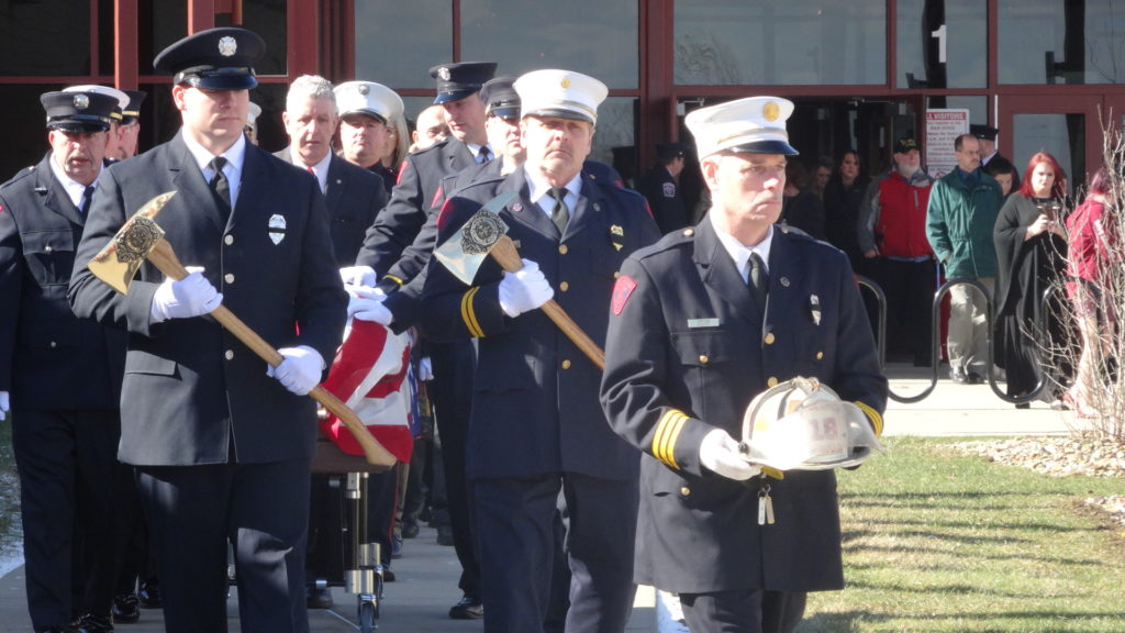 Dave Coffy, in white hat and holding an ax, marches in the funeral procession of former Fire Chief Keith Barrett in February.