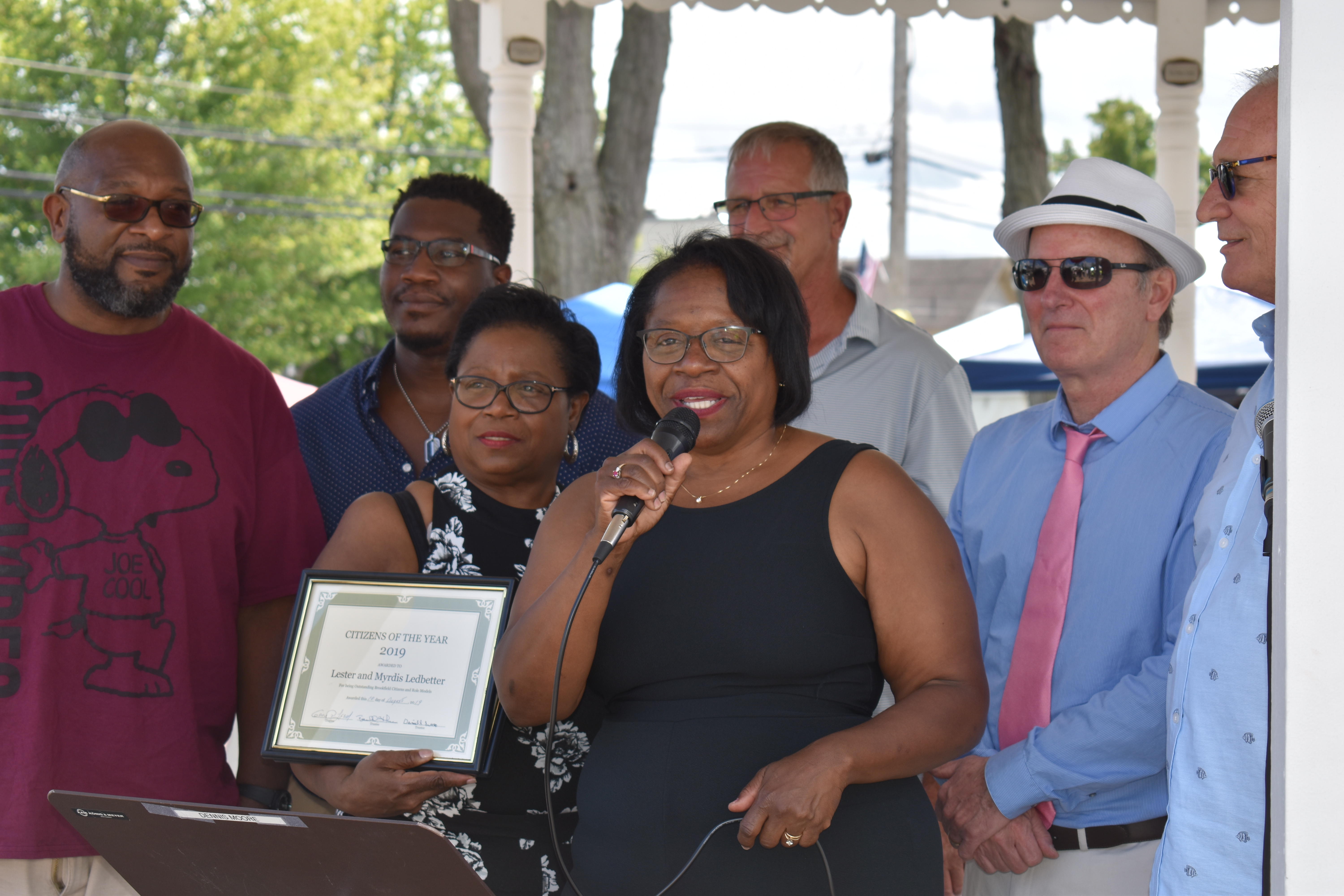 Toni-jean Glover, with microphone, accepts the Citizen of the Year award presented to her parents, Eugene and Myrdis Ledbetter. Also shown are, from left, Glover's nephews, John Ross and Eugene Ledbetter, and sister, Leslie Patterson, and Brookfield Trustees Ron Haun, Gary Lees and Dan Suttles.