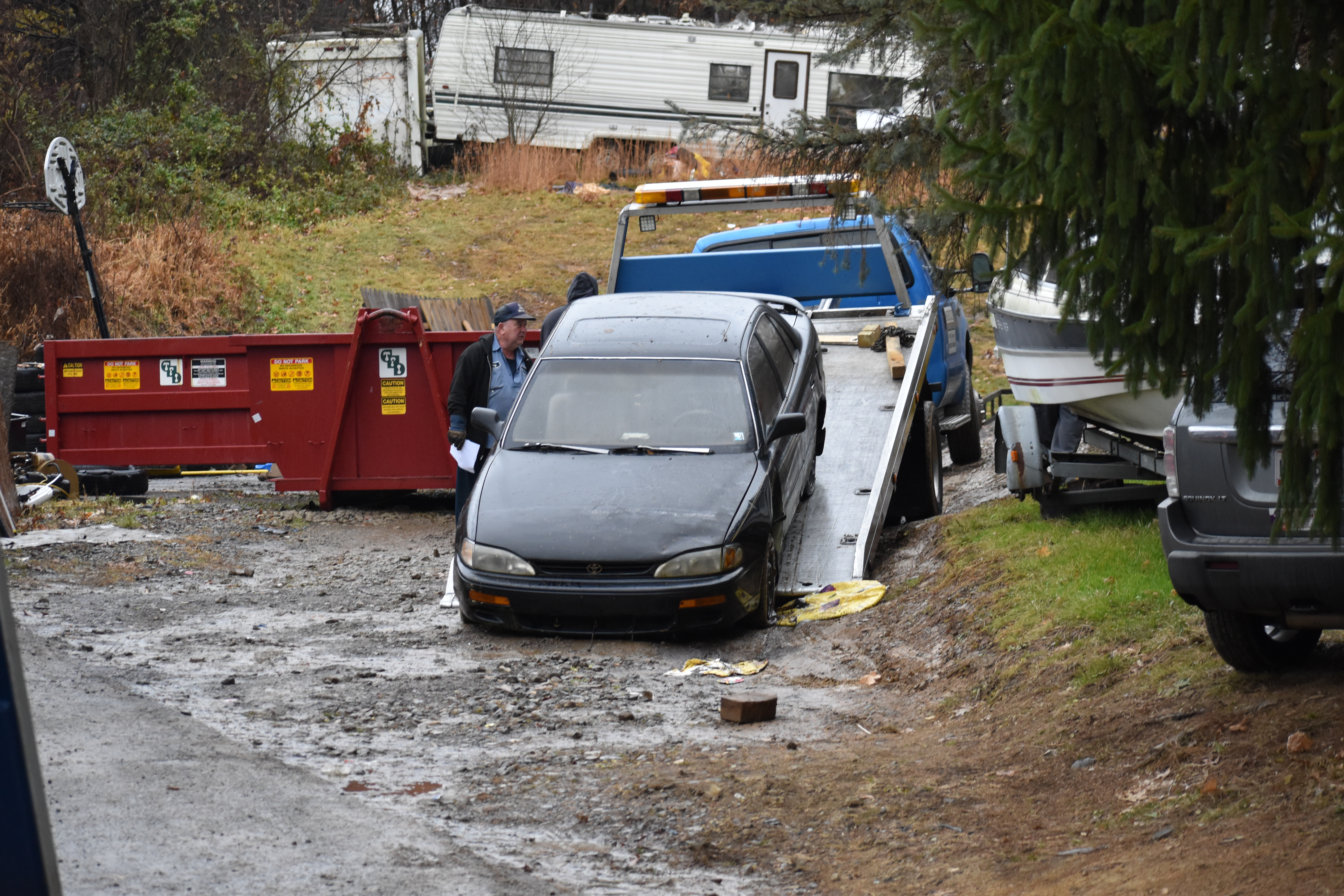 An employee of Schultz Towing and Recovery loads a car for removal from the Phillips property.