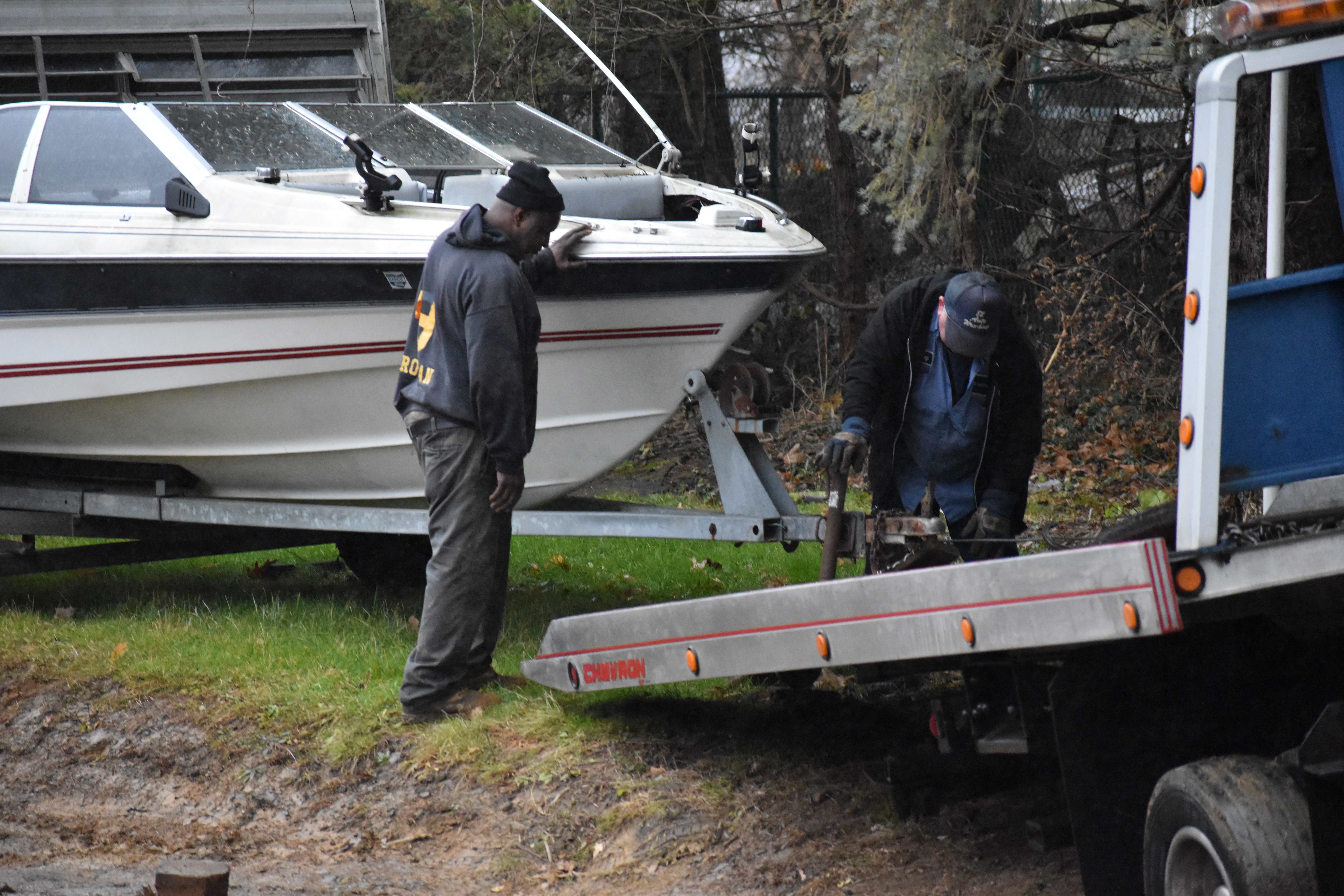 Tommie Phillips, left, watches as an employee of Schultz Towing and Recovery tries to position a boat trailer for loading on a wrecker.