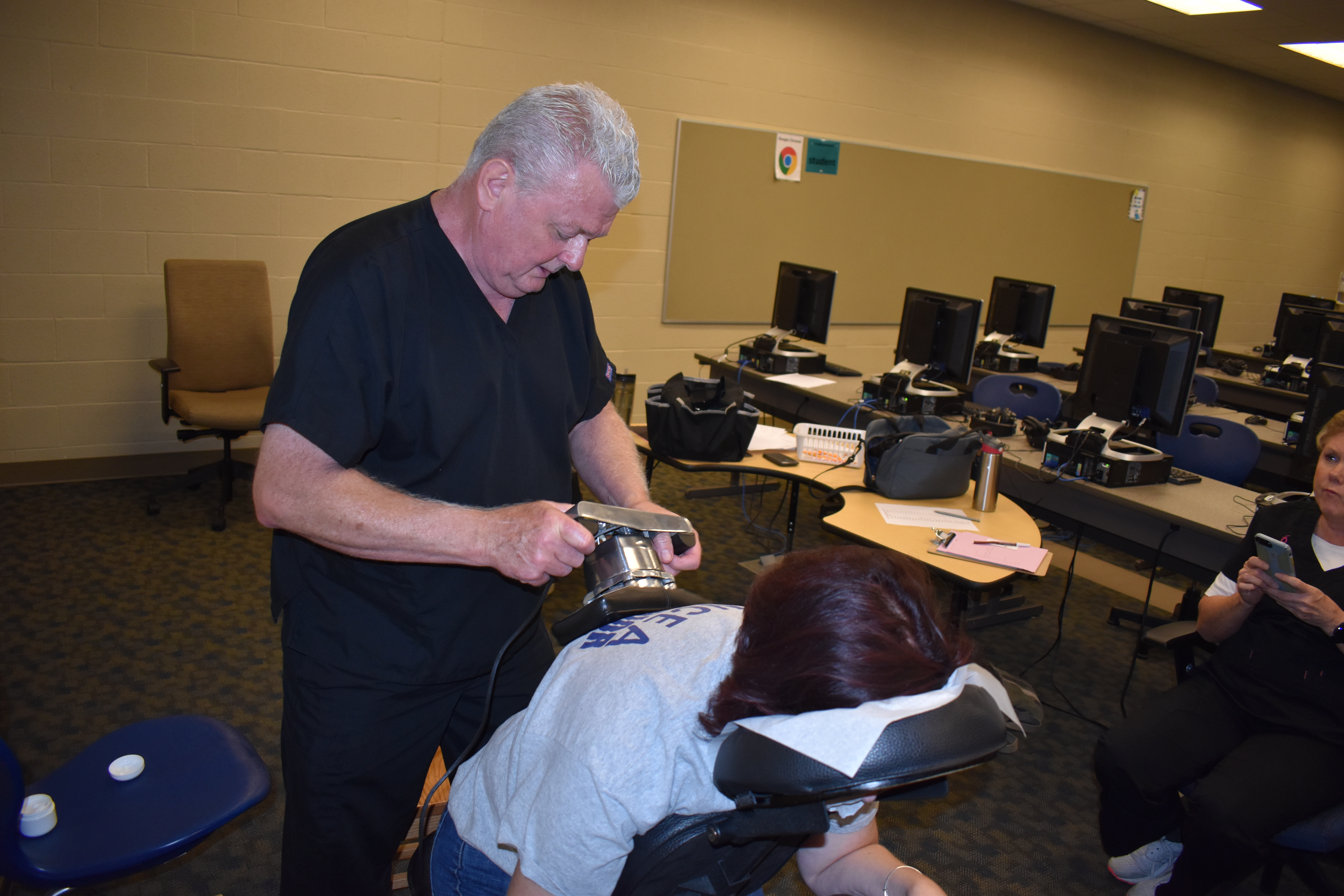 Licensed massage therapist Dave Hartman applies electronic stimulation to Brookfield High School intervention specialist Denise Hardway. Hartman offered free massages to school employees.