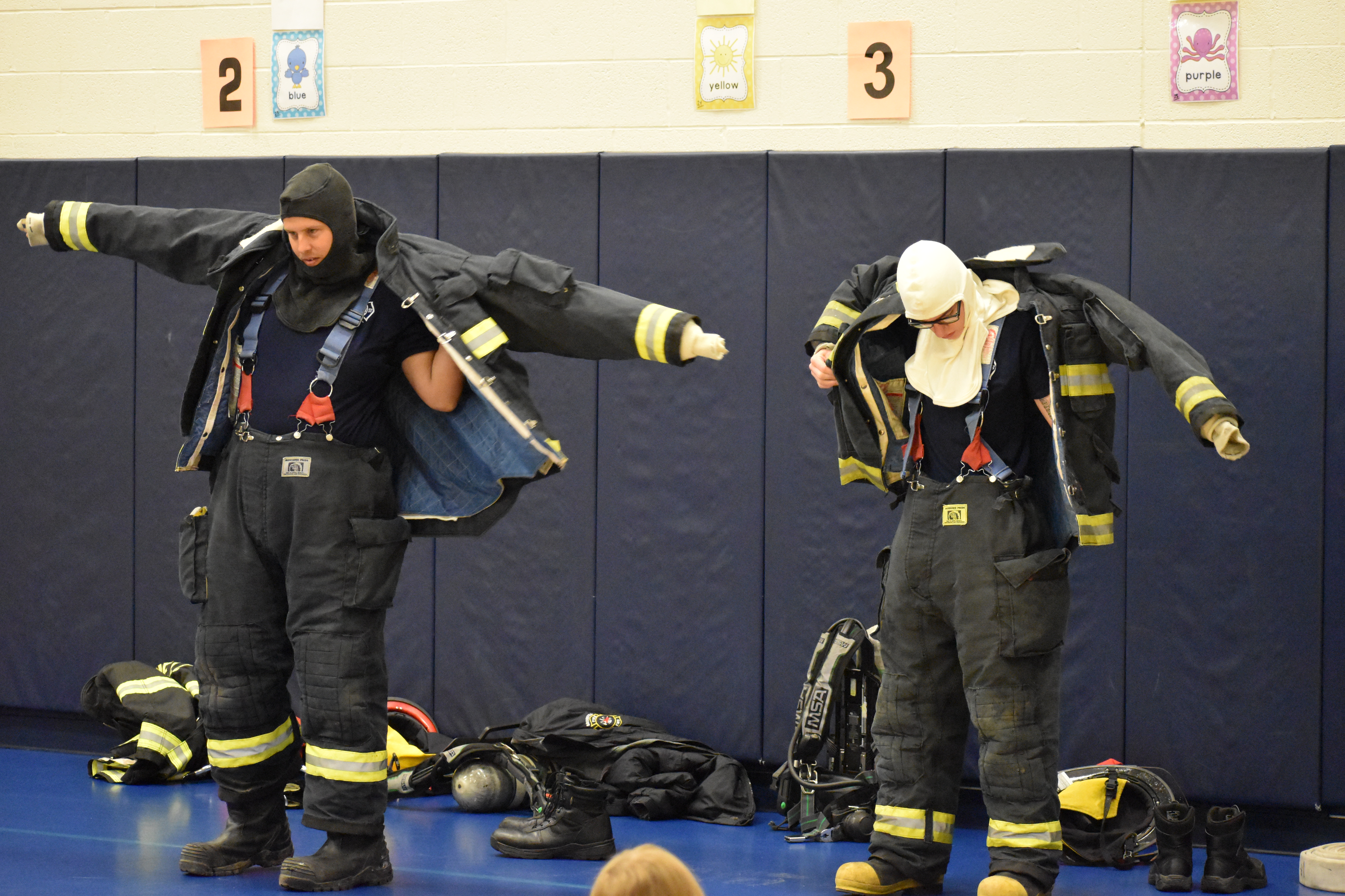 Jeremy Gless, left, and Dale May show how to put on their fire suits.