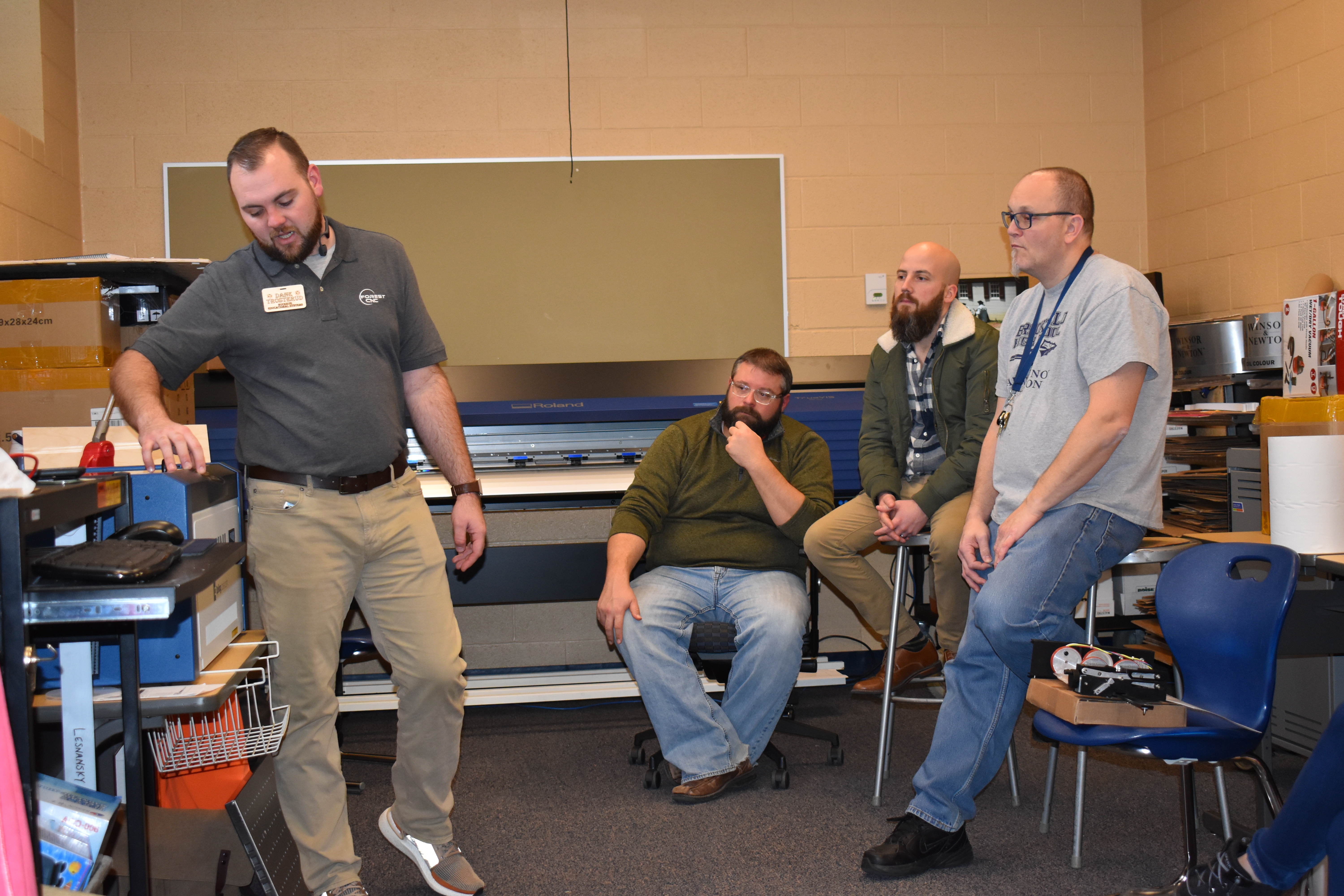 Dane Troserud, left, explains the operation of a laser cutter to Brookfield teachers, from right, Jim Haywood, Joe Meyer and Ken Iser.