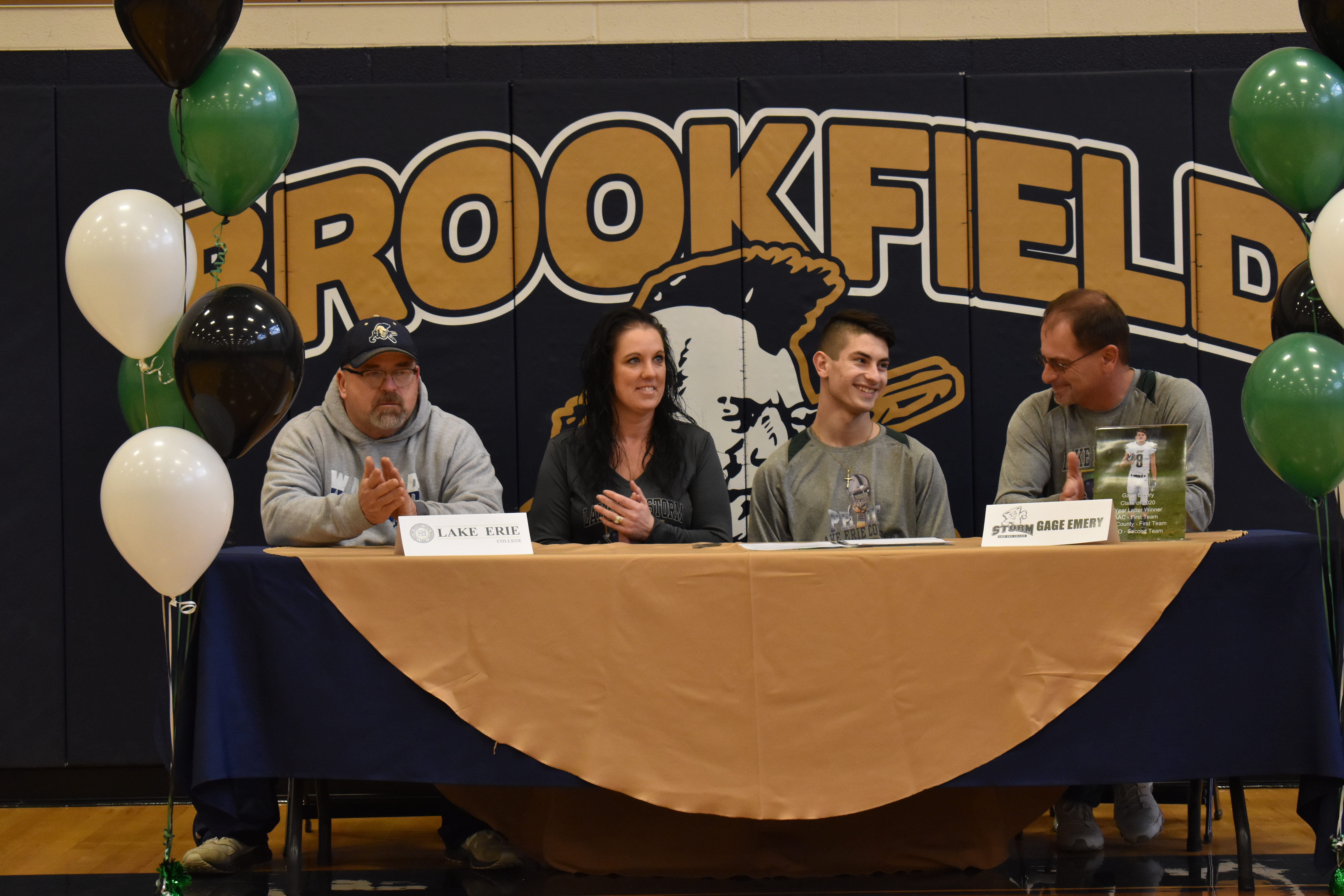 Brookfield Football Coach Randy Clark, left, and Danielle and Keith Emery applaud Brookfield High School senior Gage Emery after he signs his letter of intent to play football at Lake Erie College in Painesville.