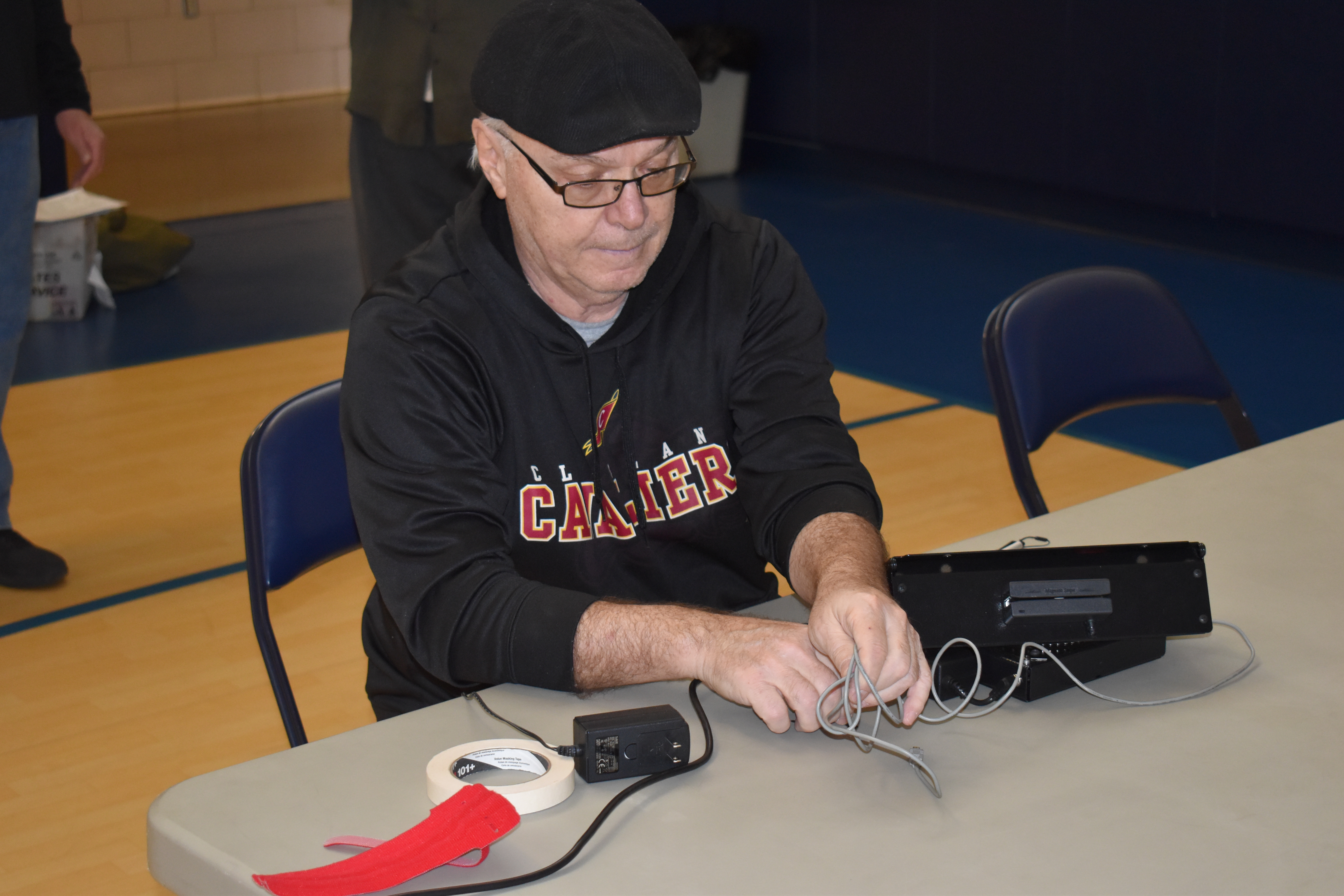 Mike D'Orio sets up electronic equipment in the gym at Brookfield Elementary School, where several Brookfield precincts vote. His work could be for naught as Gov. DeWine said he will seek to delay the election set for Tuesday, March 17, until June 2.