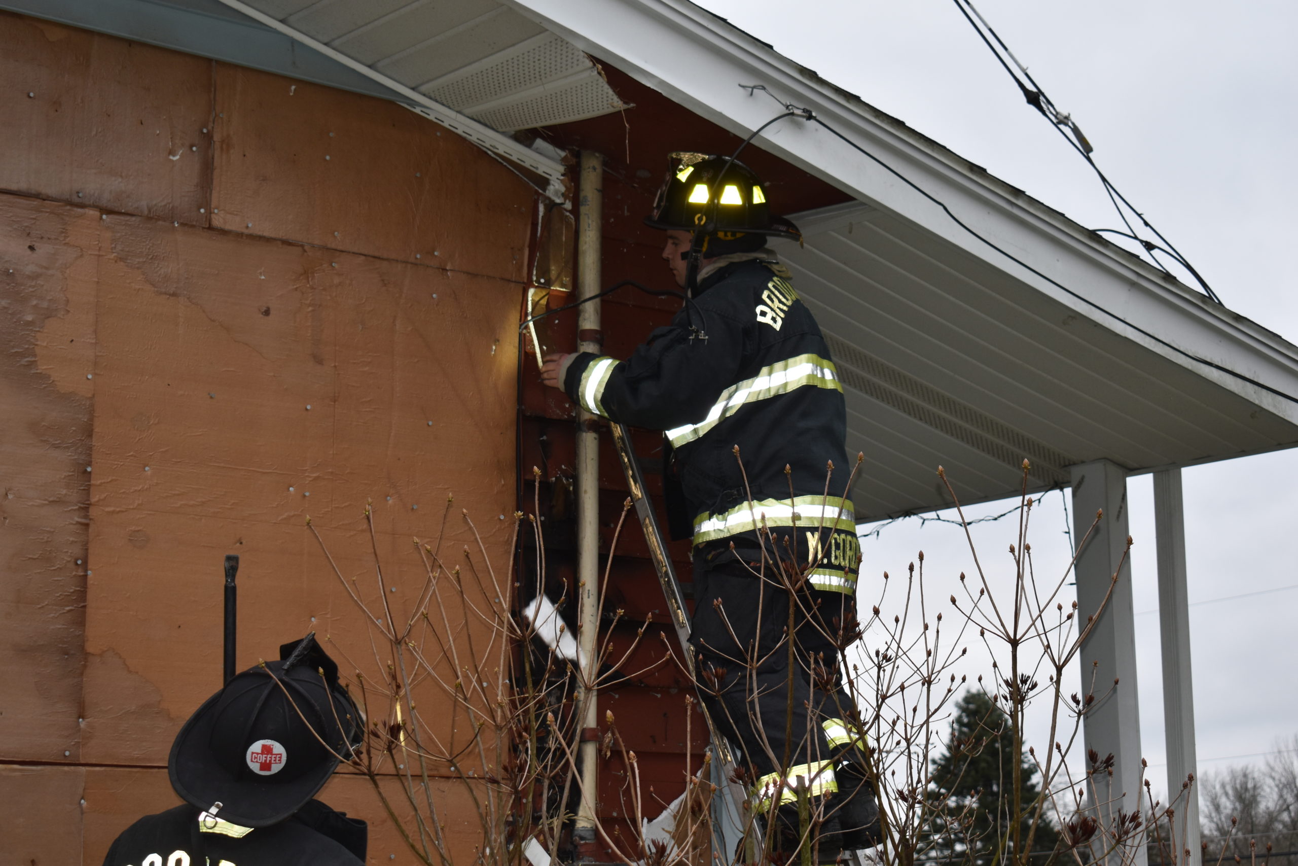 Brookfield firefighter Derek Hollander rips insulation from a home on Merwin Chase Road that suffered fire damage when a tree branch fell on electric wires.