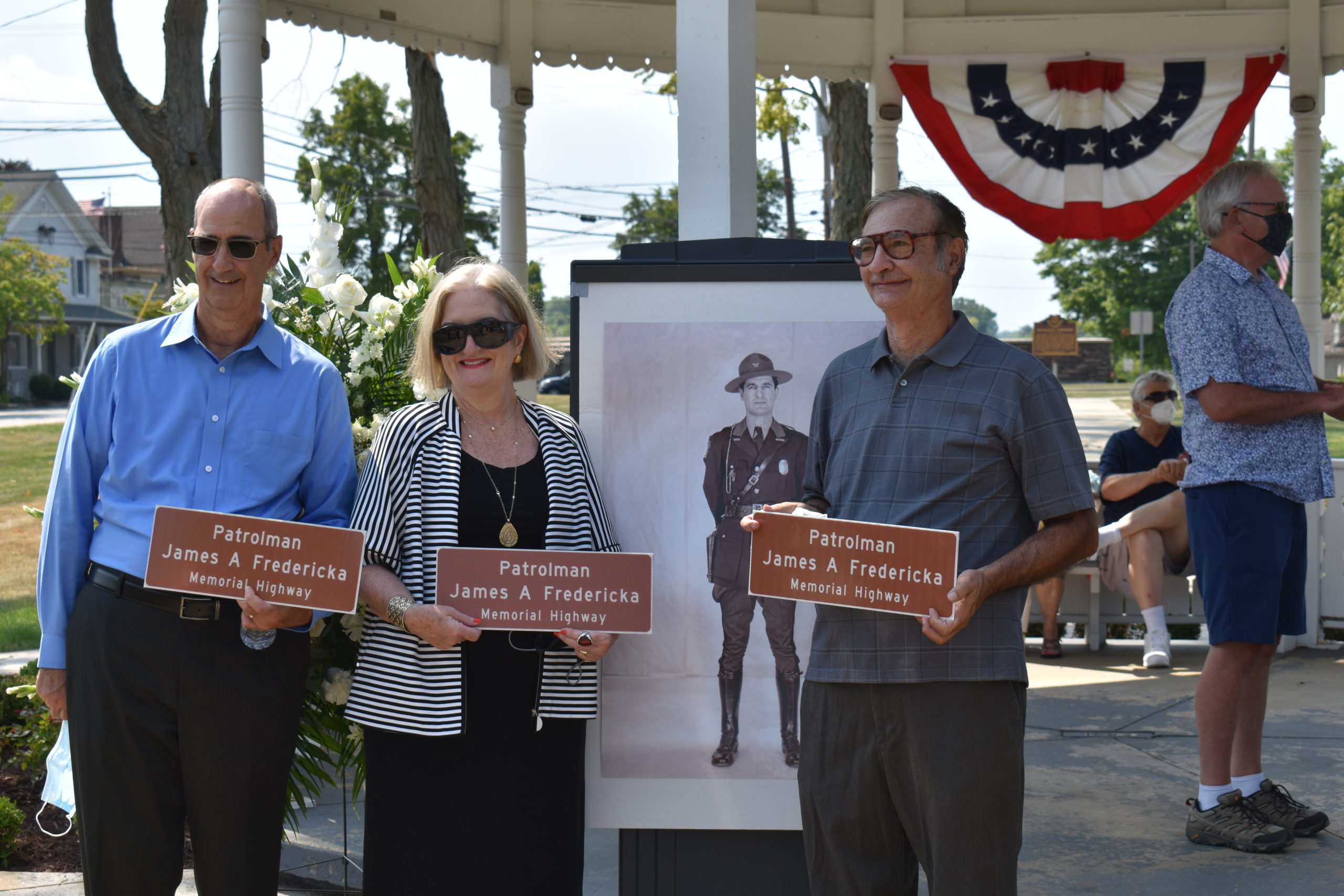Frank Fredericka, left, his sister, Theresa Klamut, and brother Joe Fredericka, stand by a photo of their father, Ohio Highway Patrolman James A. Fredericka, at a ceremony dedicating a portion of Route 7 in honor of their father.