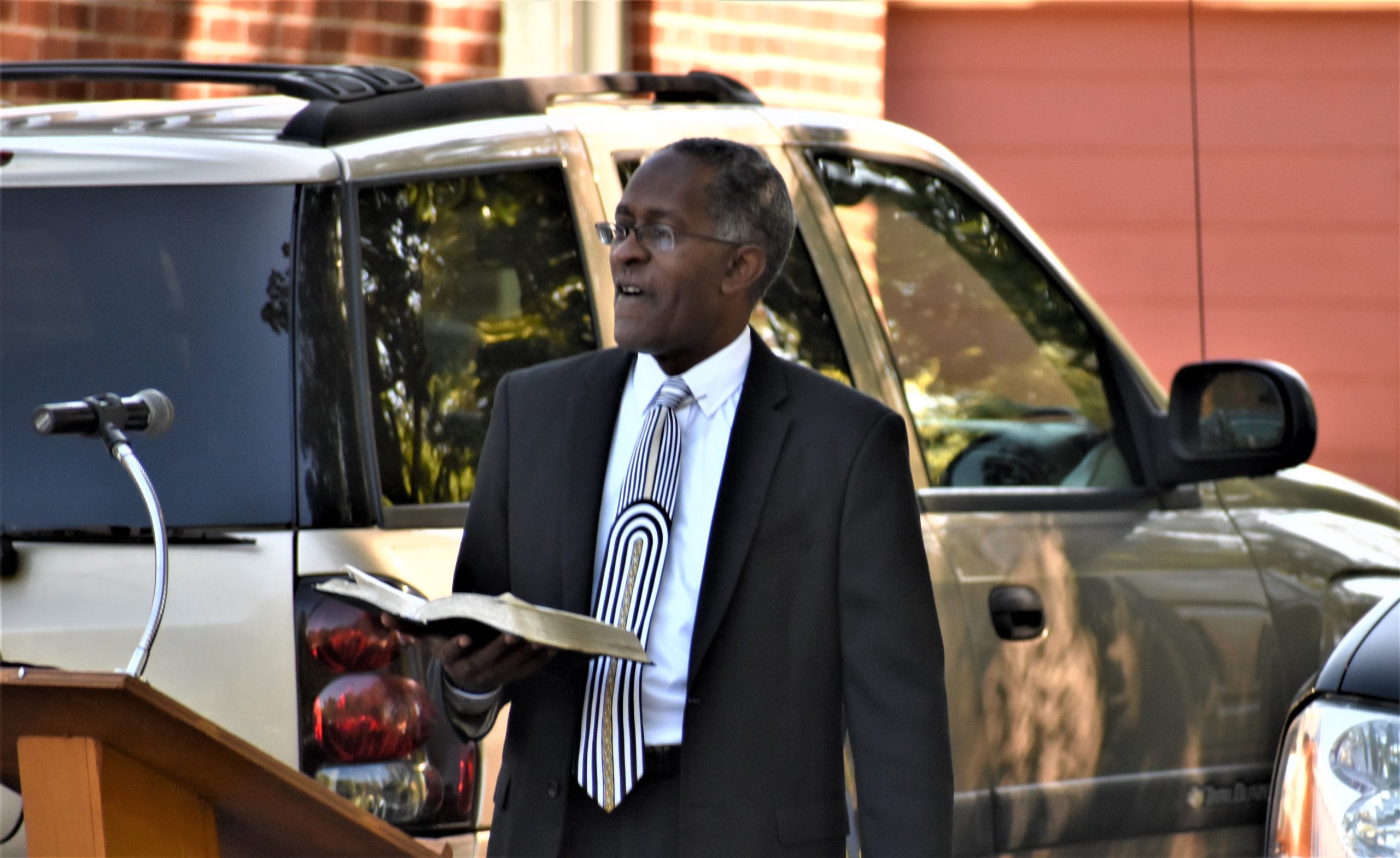 Rev. Raymond O. Brown, pastor of Mount Olive Missionary Baptist Church, left, preaches at a parking lot service Sept. 20.