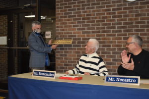 Brookfield school Supt. Toby Gibson presents the plaque that will be installed to name the Brookfield Board of Education public space as the "George Economides Board Meeting Room." Board member Jerry Necastro is at right.