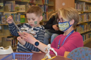 Children's librarian Nicole Bowden helps Hayden Hassey create a a skier at the Brookfield Branch Library of the Warren Trumbull-County Public Library. Hayden, 4, visited the library on its 40th birthday.