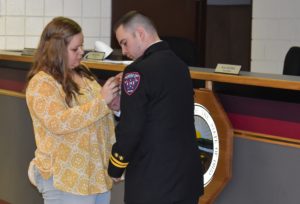 Kristy Hollander pins the captain's badge on her husband, Derek, at the May 3 Brookfield trustees meeting, when he was promoted to the command staff position in the Brookfield Fire Department.