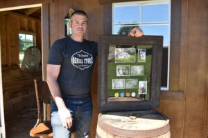 Jeff Ford, holding a memorabilia board of the Green Parrot, Masury, stands in front of the new saloon that has been built in the historical village at the Trumbull County Fairgrounds.