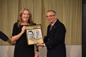 Robin Hoffman accepts the induction of her father, James Hoffman Jr., into the Brookfield Distinguished Alumni Hall of Fame. Committee member Dan Deramo is at right.