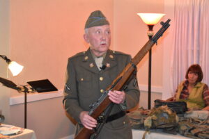 World War II re-enactor Gabe Illes of Bristol presents his M1 rifle at the November meeting of the Brookfield Township Historical Society. Illes talked about the storming of Normandy on D-Day, what the life of a World War II soldier was like and the equipment soldiers used. Society President Barbara Stevens is at right.