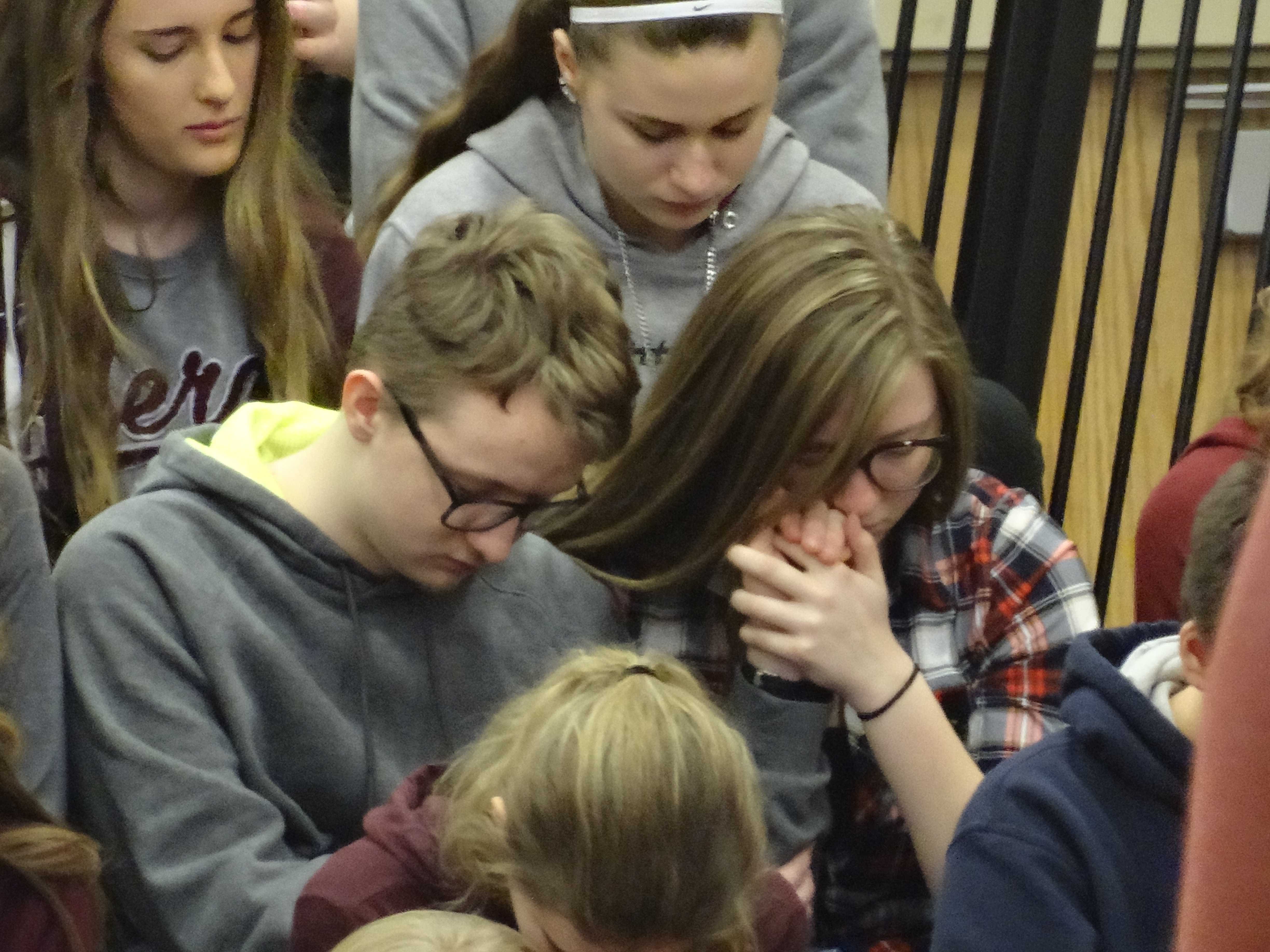 Two Brookfield High School students reach out to each other for support during the reading of victim biographies during the school's observance of National Walkout Day March 14.