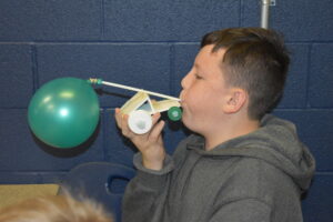 Kyle Fisher blows up the balloon that powers his rocket car in his seventh-grade STEM class.