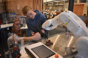 Robotics teacher Josy Kirila and student Josh Schell try to figure out why the school's Kuka robot is not working properly.