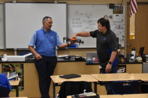Drone teacher Tim Reinsel, right, hands one of the class drones to Jason Straka, who detailed how drones are being used in a variety of industries.