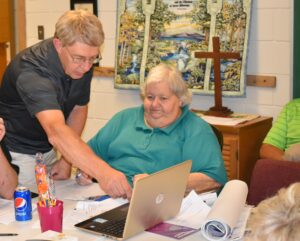 Karen Saker, right, looks on as James Hoffman III shows her something on a computer in this 2019 photo.