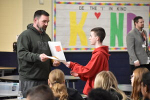 Brookfield Middle School wrestling coach Ed Morrison hands a certificate to seventh-grade student Landen Erl.
