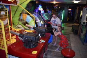 In photo at left, Hailee Finecey pulls the handle on a video game at RC3's Arcade. Iris Zucco is with her.