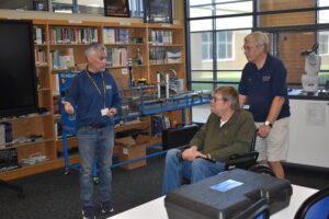 Brookfield school Supt. Toby Gibson explains the workings of the school's Industry 4.0 and Robotics labs for Brookfield Optimist Club members Jay Hearn, in wheelchair, and James Hoffman III.