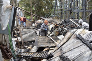 Hartford Greenhouses owner Phil Wilhelm separates debris after a fire destroyed a storage building and four greenhouses.