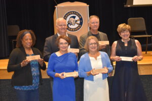 New inductees into the Distinguished Alumni Hall of Fame are, clockwise from left, Carmen Ledbetter, Col. Donald Shaffer. Lt. Col. Emmett Shaffer, Dr. Victoria Husted Medvec, Dr. Deborah Vasbinder Dillon and Dr. Darlene Vasbinder-Calhoun. They hold plaques made from the old middle school gym floor.