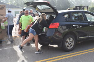 Volunteers load free household products into an SUV a charity giveaway Sept. 16 in Masury.