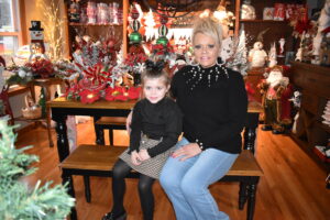 Roseann Sereday and her granddaughter, Milania, sit among the Christmas items for sales at La Bella Boutique. Milania is the namesake for the children's clothing section.