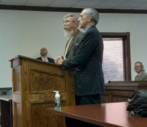 Kurt Betts, at podium left with attorney Robert Shaker, is shown at his plea hearing in Trumbull County Eastern District Court. Walter Simmons is seated at right and Simmons' attorney, Dimitrios Makridis, is at left.