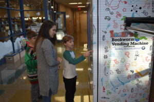 Bryan Martell pushes buttons to select a book from the book vending machine at Brookfield Elementary School. With him are Amanda O'Neill and Vincent Avery.