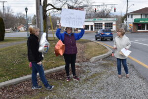Mary Lou Reder holds up a sign soliciting signatures for a petition to save Coalburg Lake. Also with her are Patti Mikula, left, and Darla Bizub.