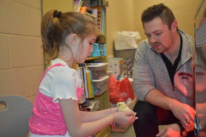 Leigha Sutton holds a newly hatched chick at Brookfield Elementary School. Sky O'Donnell, at right, runs the elementary school's afterschool program for Youngstown State University.