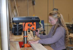 Brookfield High School student Leah Wlodarski drills holes in lumber as part of a project to make bed frames for Sleep in Heavenly Peace.